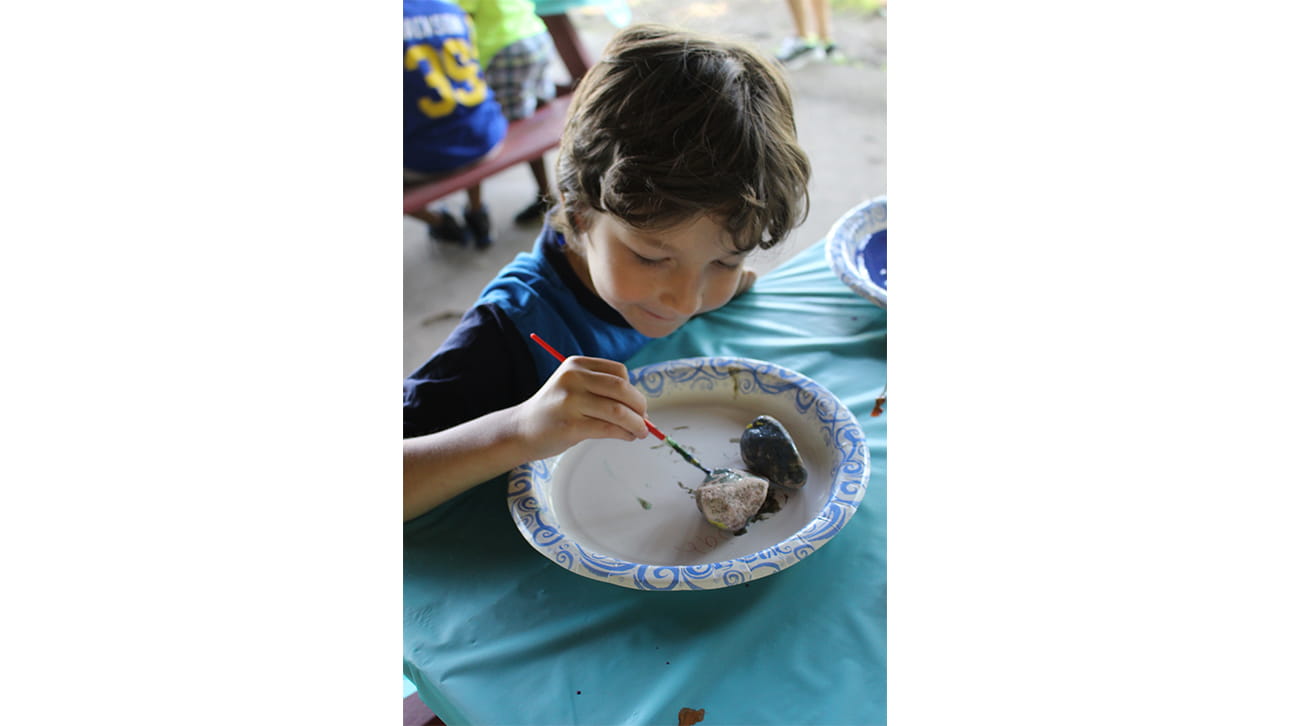 young boy painting a rock at CompassionNet's SibsROCK! day 