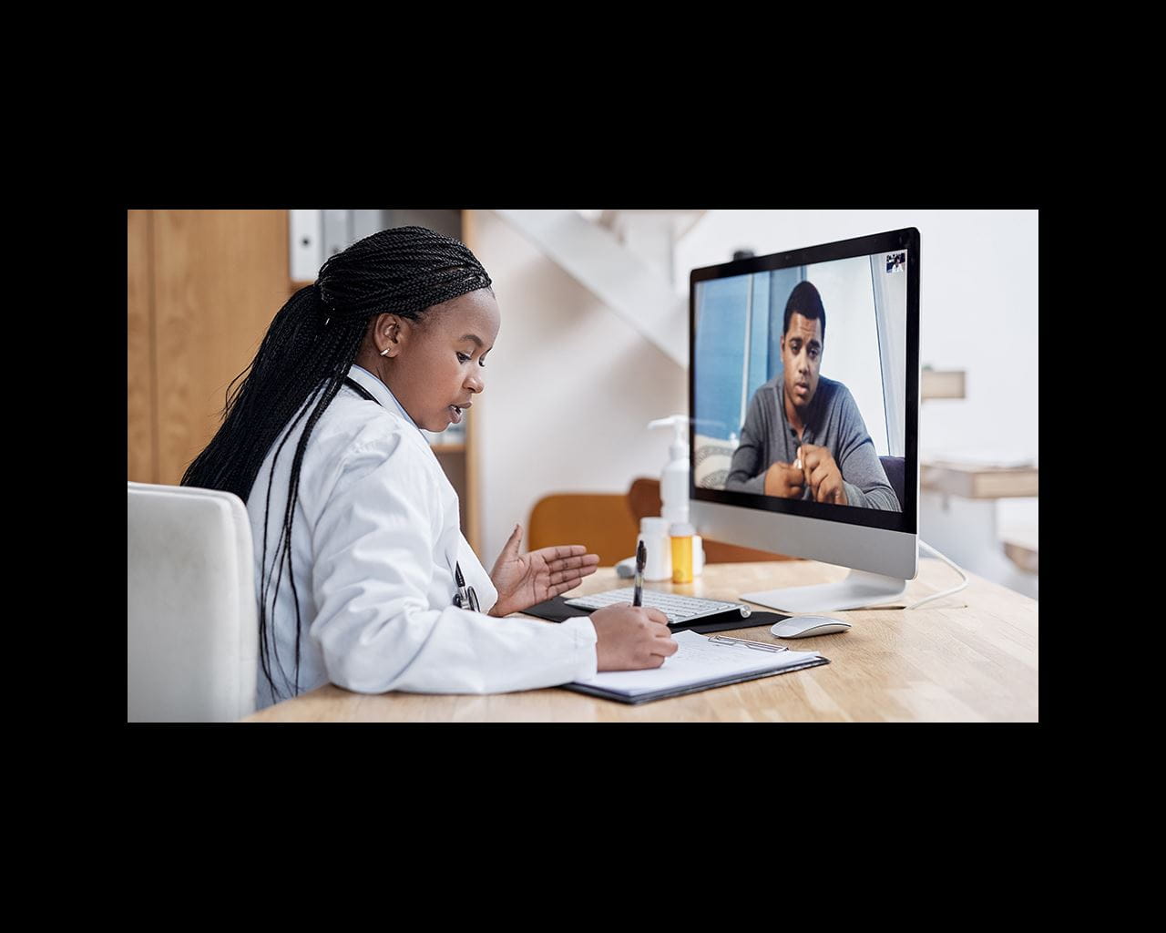 Female provider writes notes while on a virtual health appointment with a patient