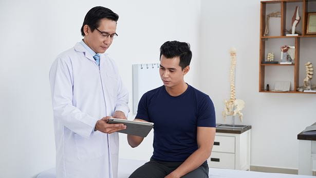 male doctor talking to a male patient about his back pain