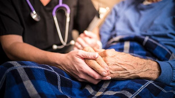 Nurse holding a senior's hand in a nursing home