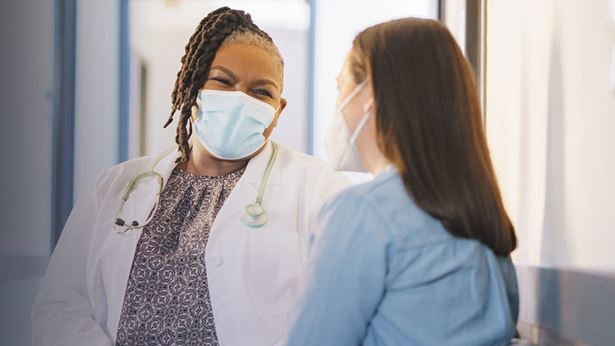 provider with face mask talking to patient in face mask